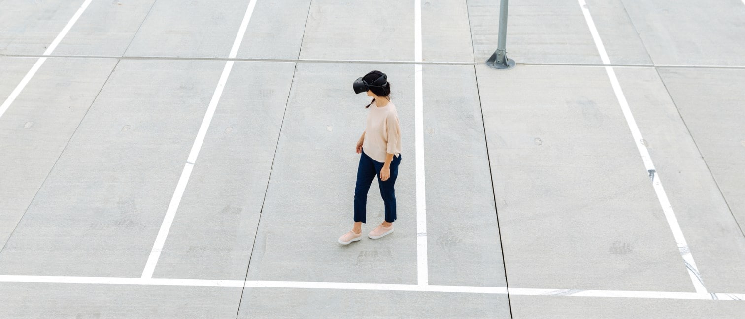 Woman walking on a parking lot with VR glasses.